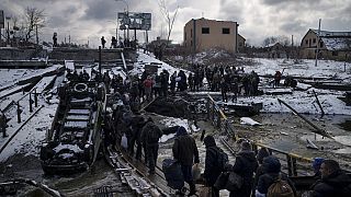 Ukrainians cross an improvised path under a destroyed bridge while fleeing Irpin, in the outskirts of Kyiv, Ukraine