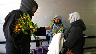 Un prete distribuisce tulipani alle donne fuggite dall'Ucraina, in occasione della Giornata internazionale della donna alla stazione ferroviaria di Przemysl, Polonia