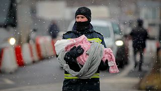 A firefighter holds the baby of a refugee fleeing the conflict from neighboring Ukraine at the Romanian-Ukrainian border, in Siret, Romania, Monday, March 7, 2022.