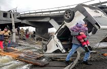أشخاص يعبرون طريقًا تحت جسر مدمر أثناء فرارهم من بلدة إيربين بالقرب من كييف ، أوكرانيا ، يوم الاثنين، 7 مارس 2022.
