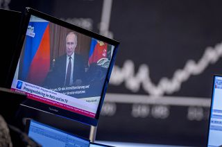 Russia's President Vladimir Putin appears on a television screen at the stock market in Frankfurt, Germany, Feb. 25, 2022. Russia is revving up its propaganda machine.