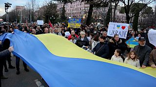 Protestors hold a massive Ukrainian flag during a rally in front of Russia's Embassy in Tirana.