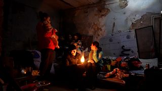 Residents of Mariupol, in shelter around oil lamp.