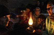 Mariupoli lakosok ülnek egy óvóhelyen március 6-án egy olajlámpa körül.