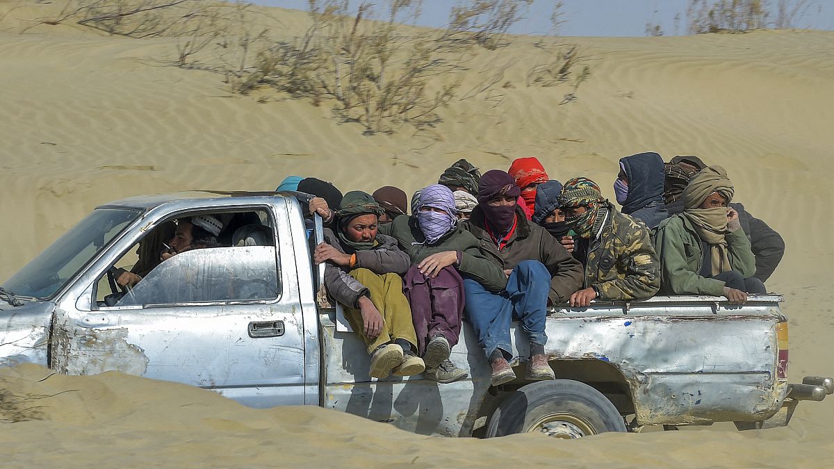  مهاجرون أفغان يركبون شاحنة صغيرة على طول طريق صحراوي باتجاه الحدود الأفغانية الإيرانية في نمروز، في 17 فبراير 2022 