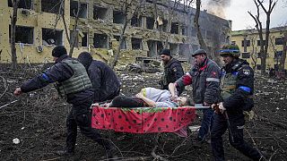 Empleados y voluntarios de emergencias ucranianos llevan a una mujer embarazada herida desde el hospital de maternidad dañado por los bombardeos en Mariupol, Ucrania