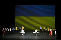 Ballerini del Kyiv City Ballet si esibiscono davanti alla bandiera ucraina, proiettata su uno schermo al Théâtre du Chatelet di Parigi