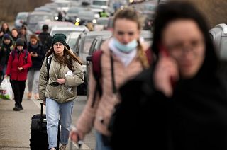 FILE - Ukrainian refugees walk along vehicles lining-up to cross the border from Ukraine into Moldova.