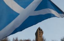 A Scottish Saltire flag blows in the wind near the Wallace Monument, Stirling, Scotland.