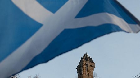 A Scottish Saltire flag blows in the wind near the Wallace Monument, Stirling, Scotland.