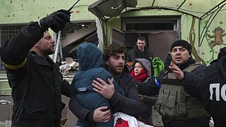 Un homme fuit l'hôpital pédiatrique de Mariupol avec son enfant après un bombardement, le 9 mars 2022