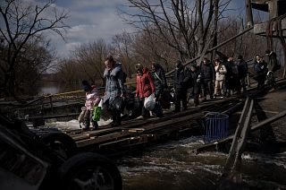 Ukrainians cross an improvised path under a destroyed bridge while fleeing Irpin, on the outskirts of Kyiv, Ukraine, Wednesday, March 9, 2022. 