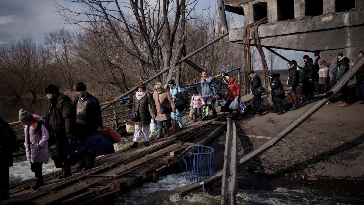 Ukrainians cross an improvised path under a destroyed bridge while fleeing Irpin, on the outskirts of Kyiv, Ukraine, Wednesday, March 9, 2022. 
