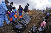 Dead bodies are placed into a mass grave on the outskirts of Mariupol