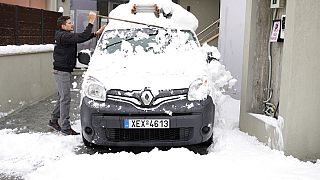 A man clears his vehicle from snow in Afidnes village, north of Athens, Greece