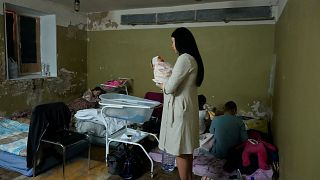 A woman holds her newborn child in the basement of a maternity hospital converted into a medical ward and used as a bomb shelter during an air raid alert, in Kyiv, Ukraine, We