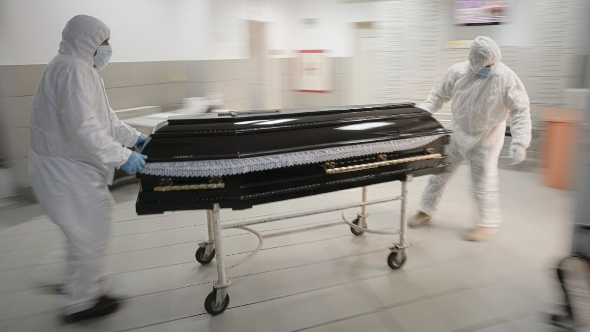 Funeral house employees remove the coffin of a COVID-19 victim from the University Emergency Hospital morgue in Bucharest, Romania, Monday, Nov. 8, 2021