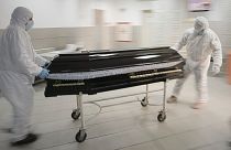 Funeral house employees remove the coffin of a COVID-19 victim from the University Emergency Hospital morgue in Bucharest, Romania, Monday, Nov. 8, 2021