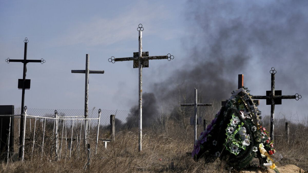 Rauch von Granateneinschlägen steigt auf, als ein Blumenkranz auf einem Friedhof in Vasylkiv südwestlich von Kiew niedergelegt wird, 12.03.2022,