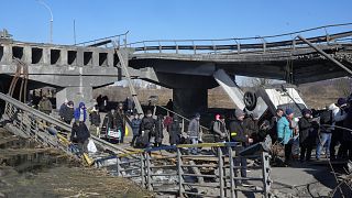Ukránok menekülnek egy szétbombázott híd mellett a Kijev melletti Irpinből