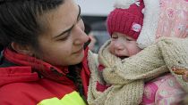 Una trabajadora de Emergencia de Rumanía consuela al bebé que llora en un campo de regugiados en la ciudad de Siret, Rumanía, el 10 de marzo de 2022.