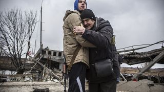 Un membre des forces ukrainiennes soutient un habitant d'Irpin, qui s'apprête à quitter sa ville, Ukraine, le 9 mars 2022