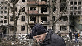 An elderly man walks outside an apartment block which was destroyed by an artillery strike in Kyiv on 14 March 2022