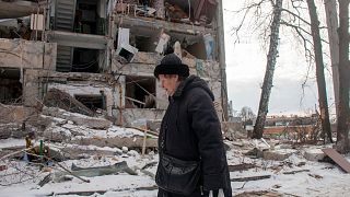 A woman walks past building damaged by shelling, in Kharkiv, Ukraine, Sunday, March 13, 2022. 