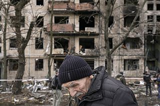 An elderly man walks outside an apartment block which was destroyed by an artillery strike in Kyiv on 14 March 2022