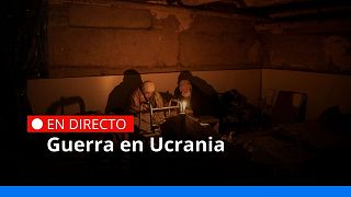 Dos mujeres iluminadas por una vela se esconden en un sótano utilizado como refugio antibombas en Irpin, en las afueras de Kiev, Ucrania