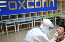 File - A medical worker takes a swab sample to test for COVID-19 from a worker at the Foxconn factory in Wuhan in central China's Hubei province Thursday, Aug. 5, 2021.