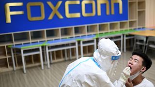 File - A medical worker takes a swab sample to test for COVID-19 from a worker at the Foxconn factory in Wuhan in central China's Hubei province Thursday, Aug. 5, 2021. 