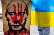 A protester holds a placard showing Vladimir Putin during a protest against Russia's invasion of Ukraine, Cyprus