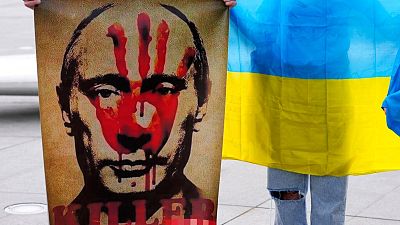 A protester holds a placard showing Vladimir Putin during a protest against Russia's invasion of Ukraine, Cyprus 
