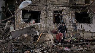 People retrieve belongings from an apartment in a block which was destroyed by an artillery strike in Kyiv, Ukraine, Monday, March 14, 2022.