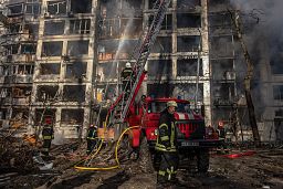 Tűzoltók dolgoznak egy tüzérségi támadásban megrongálódott lakóháznál Kijevben 2022. március 15-én.