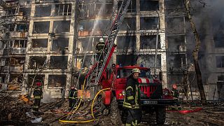 Tűzoltók dolgoznak egy tüzérségi támadásban megrongálódott lakóháznál Kijevben 2022. március 15-én.