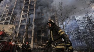 A firefighter walks outside a destroyed apartment building after a bombing in a residential area in Kyiv, Ukraine, Tuesday, March 15, 2022