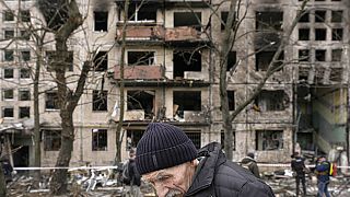 Idős férfi sétál el a találatot kapott kijevi lakóépület előtt