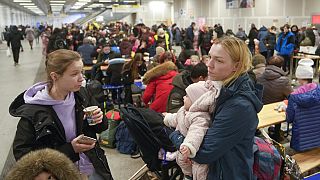 Two women with their children rest in a subway hall after fleeing from the Ukraine at the main train station in Berlin