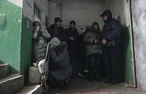 Zivilisten kauern sich in einem Kiewer Wohnhaus in einem Flur zusammen