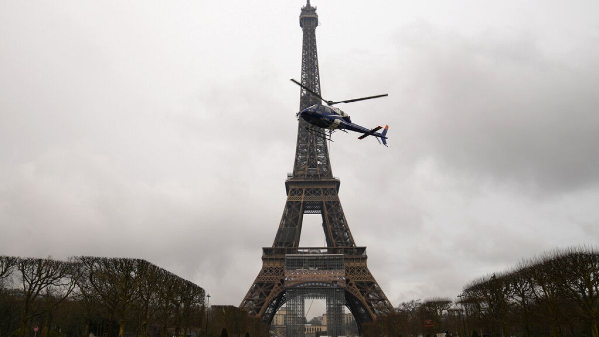 A helicopter installs a new telecom transmission TDF antenna on the top of the Eiffel Tower