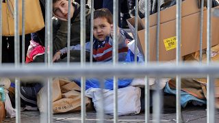 Two boys sit behind a barrier in Brussels as they wait in a registration line for people fleeing Ukraine.