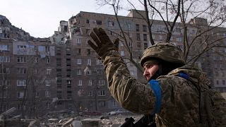 Soldado ucraniano perante edifício destruído em Mariupol