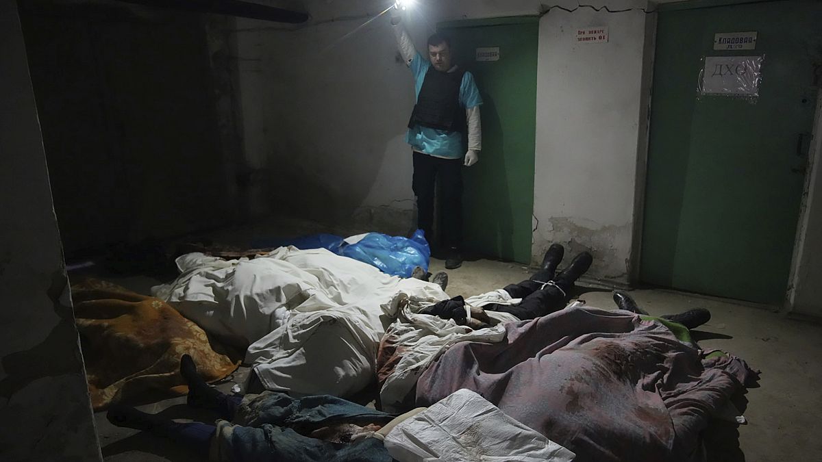 Dans le sous-sol de l'hôpital N°3 de Marioupol, un policier montre les corps de victimes d'un bombardement. 