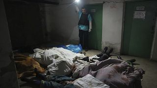Dans le sous-sol de l'hôpital N°3 de Marioupol, un policier montre les corps de victimes d'un bombardement.