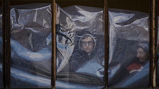 People put up plastic sheets to cover the broken windows of their apartments after parts of a Russian missile landed on an apartment block in Kyiv on 17 March 2022