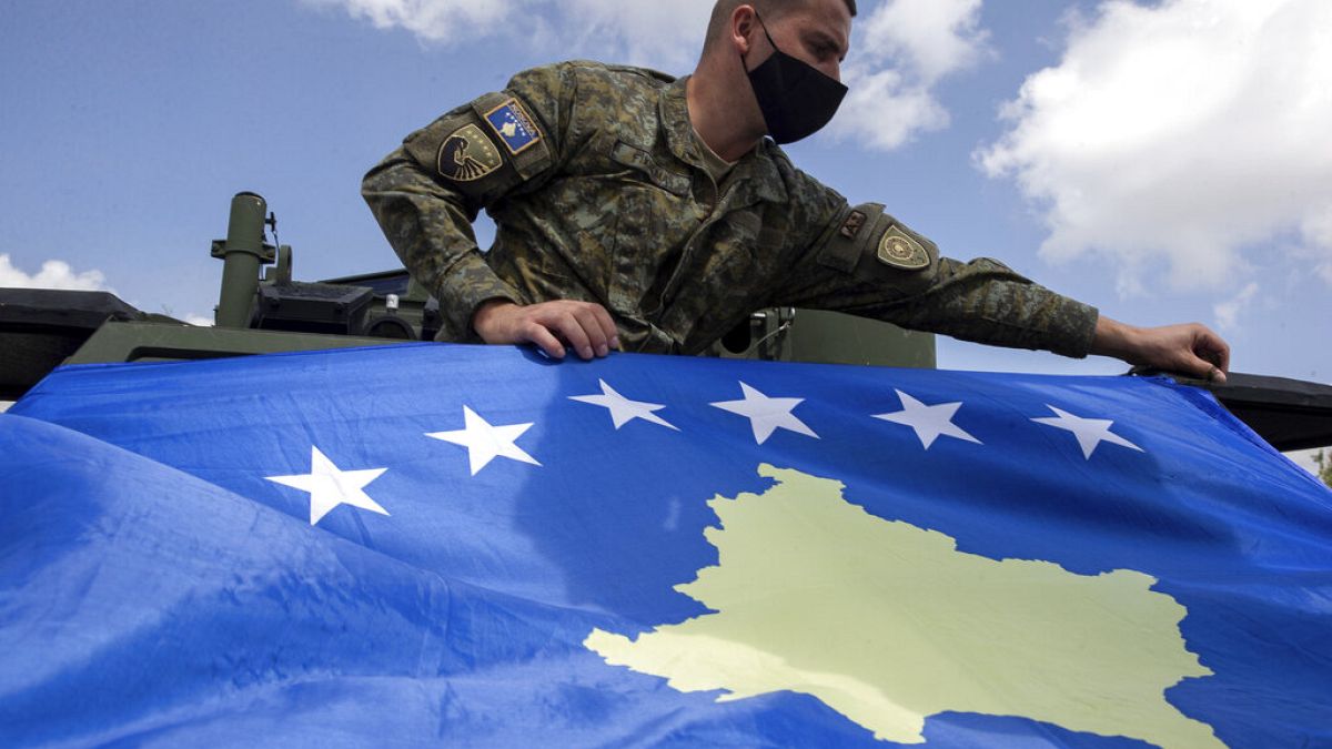 Kosovo Security Force soldier places a Kosovo flag on top of armored security vehicle donated by U.S during a handout ceremony in the military barracks Adem Jashari.