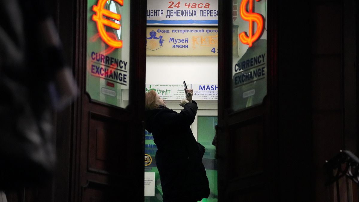 Женщина пенсионного возраста фотографирует курс валют в обменном пункте в Петербурге 25 февраля 2022