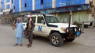 مقاتلو طالبان يلتقطون صورة بجوار مركبة تابعة للأمم المتحدة في قندوز بأفغانستان.